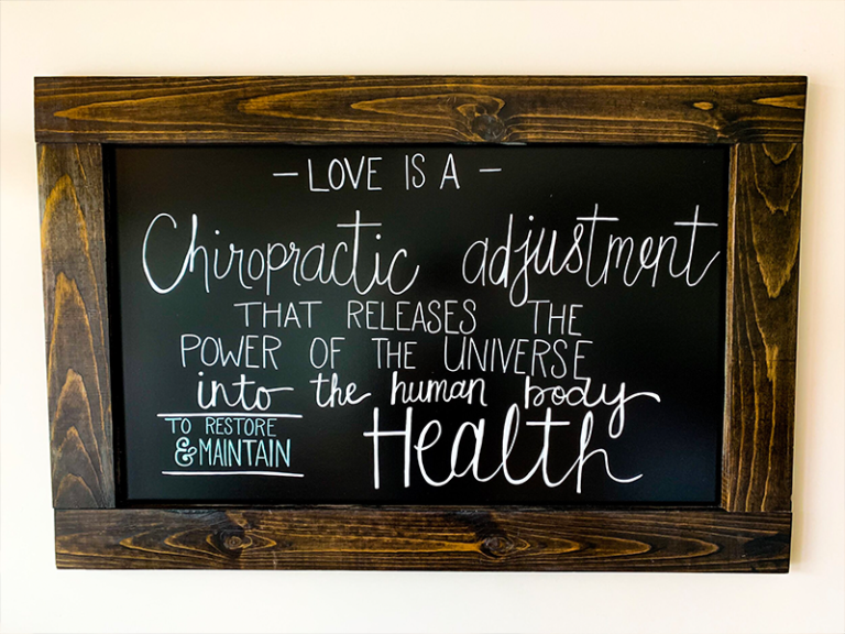 Image of chiropractic adjustment board that reads "Love is a chiropractic adjustment that releases the power of the universe into the human body to restore and maintain health."